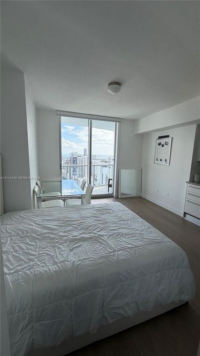 Floor-to-ceiling glass sliding door, integrated private balcony, and light-toned wood-finish flooring