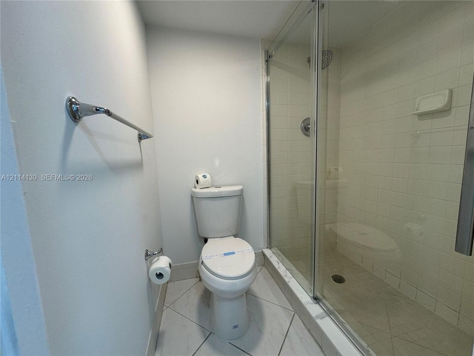 Walk-in shower with a glass enclosure, square wall tile, and polished chrome fixtures, complemented by light-toned diagonal floor tile