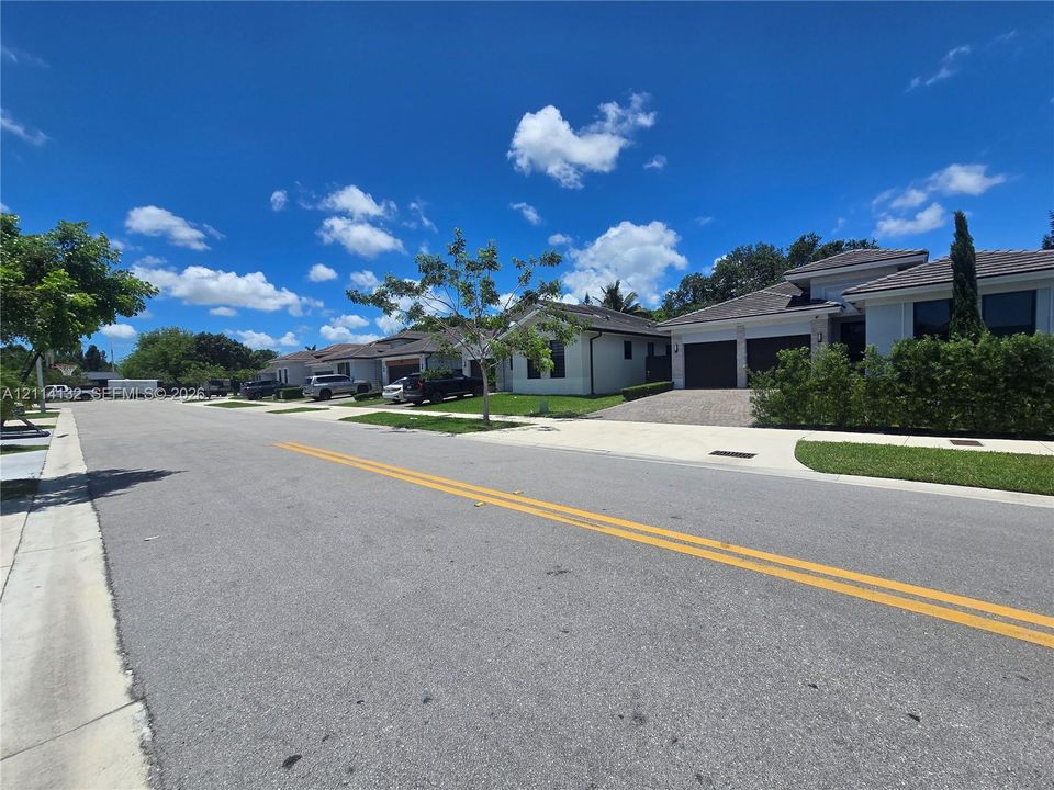 Single-story residence featuring a multi-car garage, paver driveway, light-toned exterior finish, and low-slope tile roof