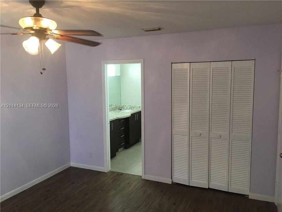 Wood-finish flooring, ceiling fan with integrated lighting, and closet with white louvered bifold doors