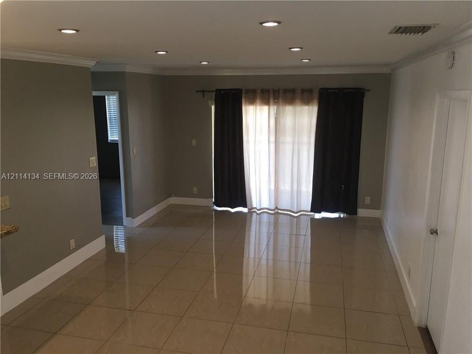 Living area featuring large-format tile flooring, recessed lighting, and crown molding