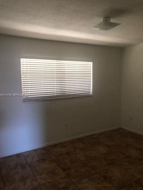 Interior room featuring neutral wall finishes, tile flooring, horizontal window blinds, and a flush-mount ceiling light fixture
