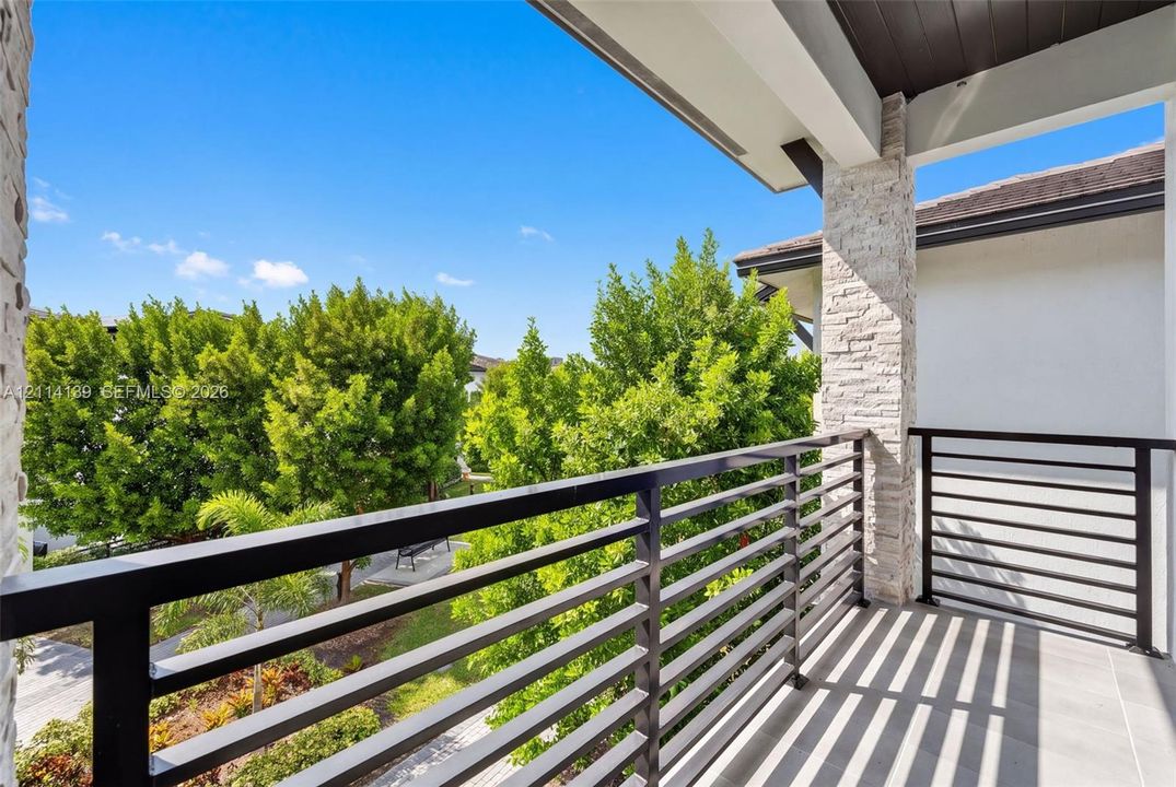 Covered balcony featuring matte black horizontal railings, stone-veneer column, and tile flooring