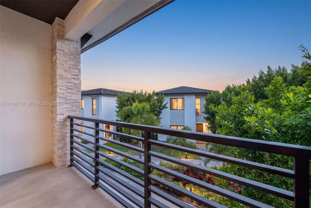 Covered balcony featuring stone-clad pillar, metal railing, and tile flooring