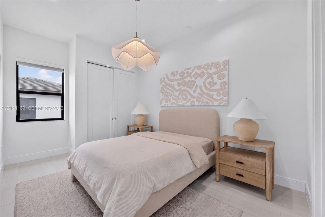 Minimalist interior featuring neutral-toned tile flooring, double-door closet with recessed handles, and a sculptural pendant light fixture