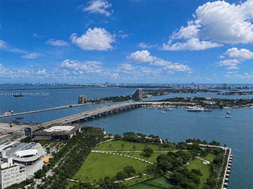 Elevated panoramic perspective featuring expansive water, multiple bridges, urban skyline, and green space