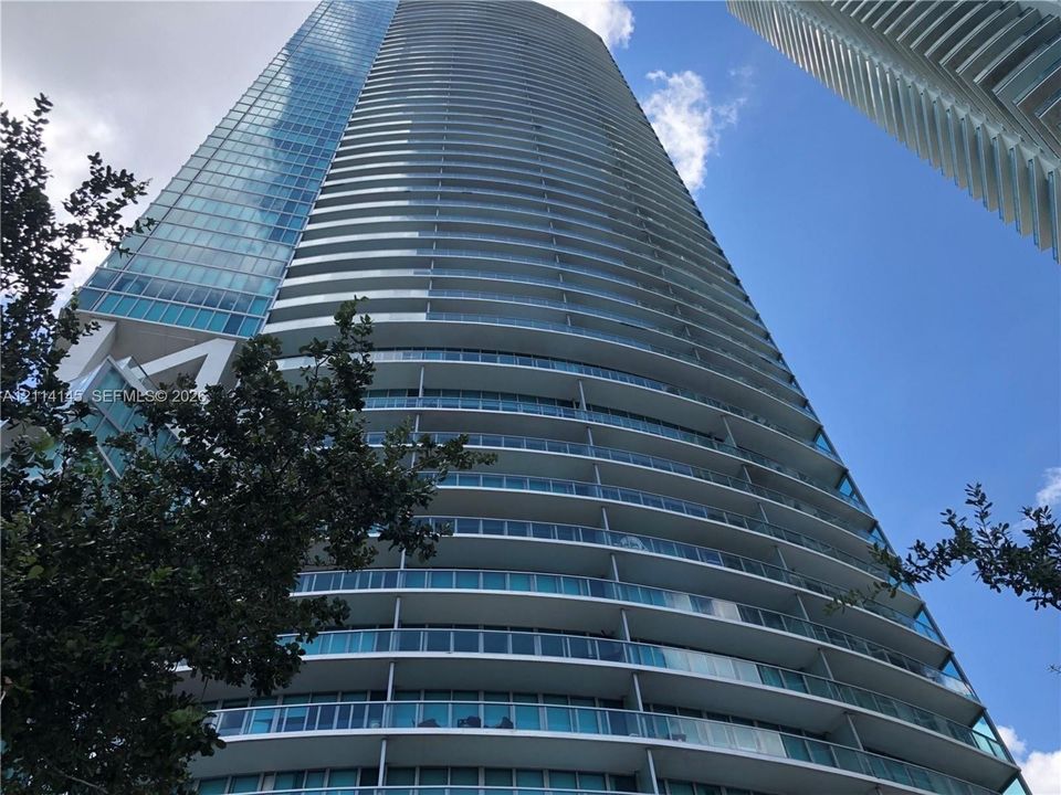 High-rise architectural structure featuring a glass facade and continuous wrap-around balconies