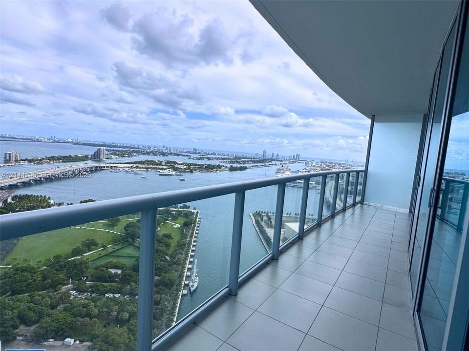 Covered balcony featuring large-format tile flooring and a glass-paneled railing