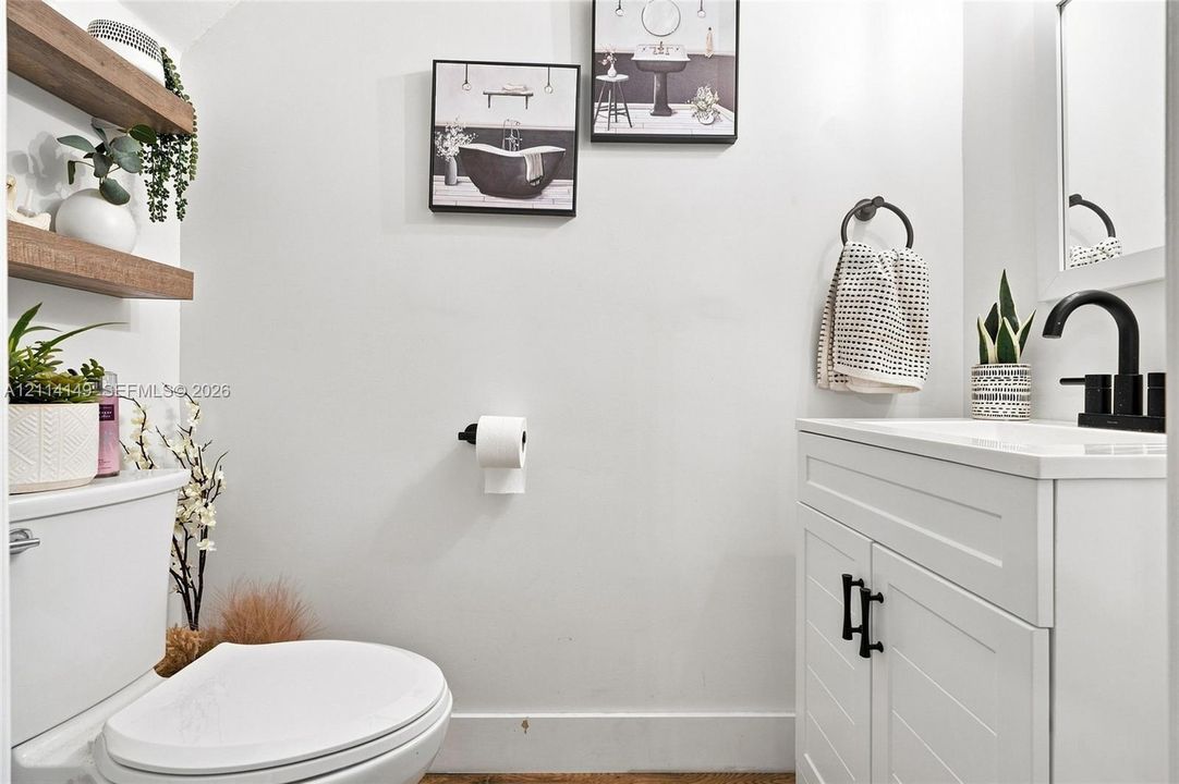 White vanity with shaker-style cabinet doors, matte black hardware, integrated sink, and matching matte black faucet