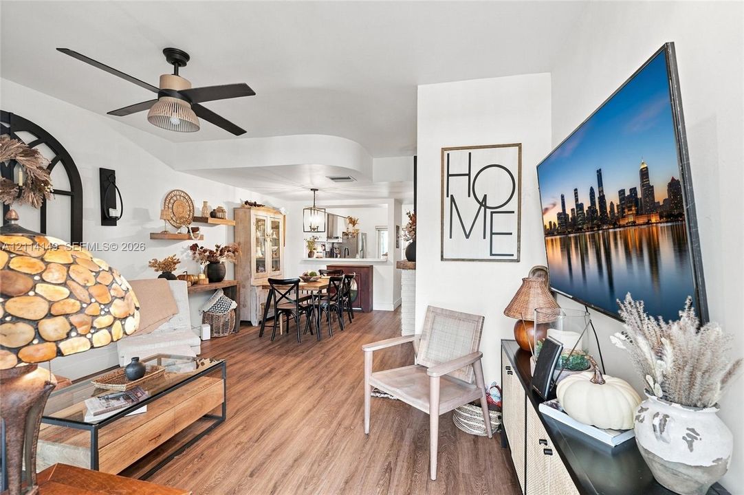 Open-concept area featuring wood-finish flooring, matte black ceiling fan, recessed lighting, and arched decorative wall element