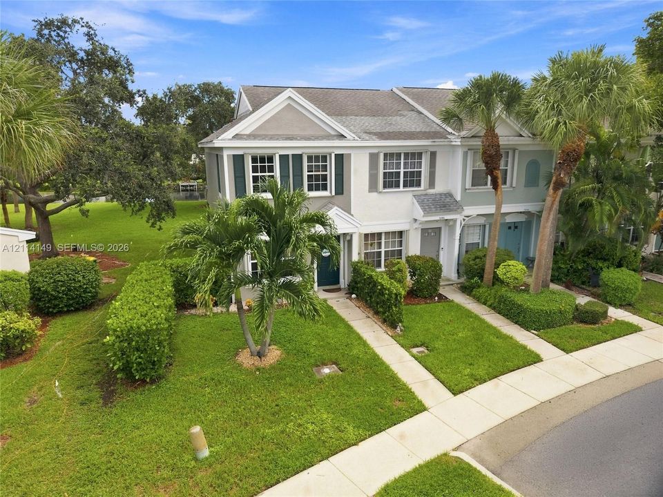 Two-story multi-unit exterior featuring light-toned siding, dark window shutters, gabled rooflines, and a concrete paver walkway