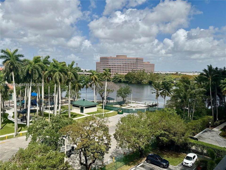 Panoramic water frontage featuring mature palm trees, landscaped grounds, and paved pathways