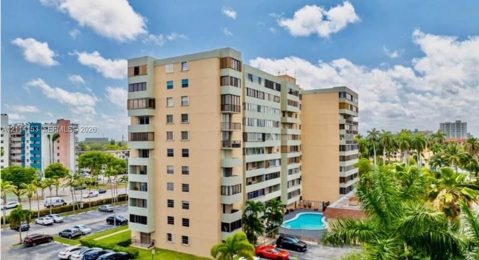 Multi-story high-rise building featuring private balconies, an on-site swimming pool, and dedicated surface parking