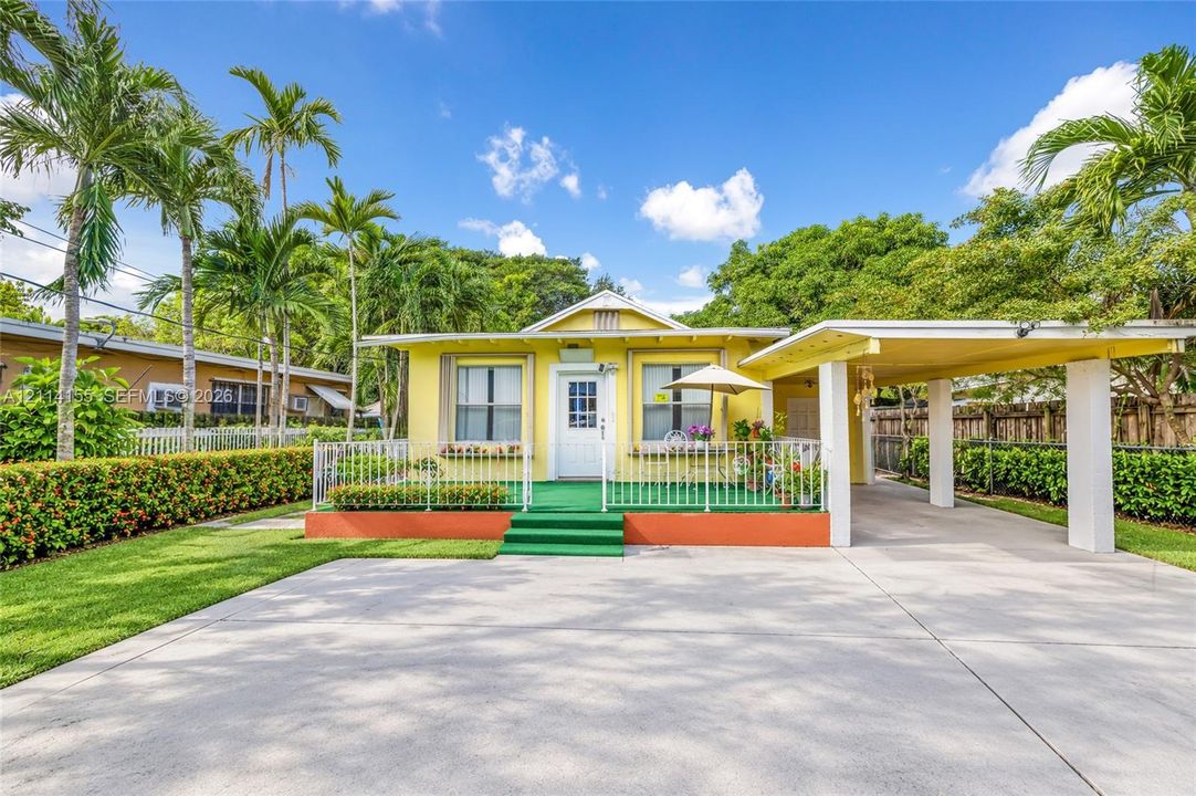 Single-story residence featuring a front porch with decorative metal railing, an attached carport, and a concrete driveway