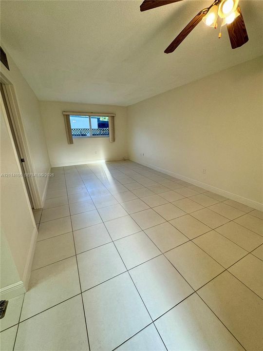Neutral-toned tile flooring, recessed window with a frame, and a multi-blade ceiling fan with integrated lighting