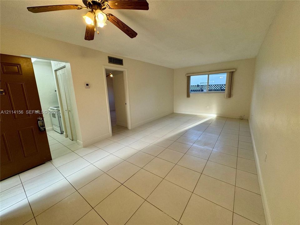 Interior featuring light-colored tile flooring, ceiling fan with integrated lighting, multi-panel entry door, and horizontal sliding window