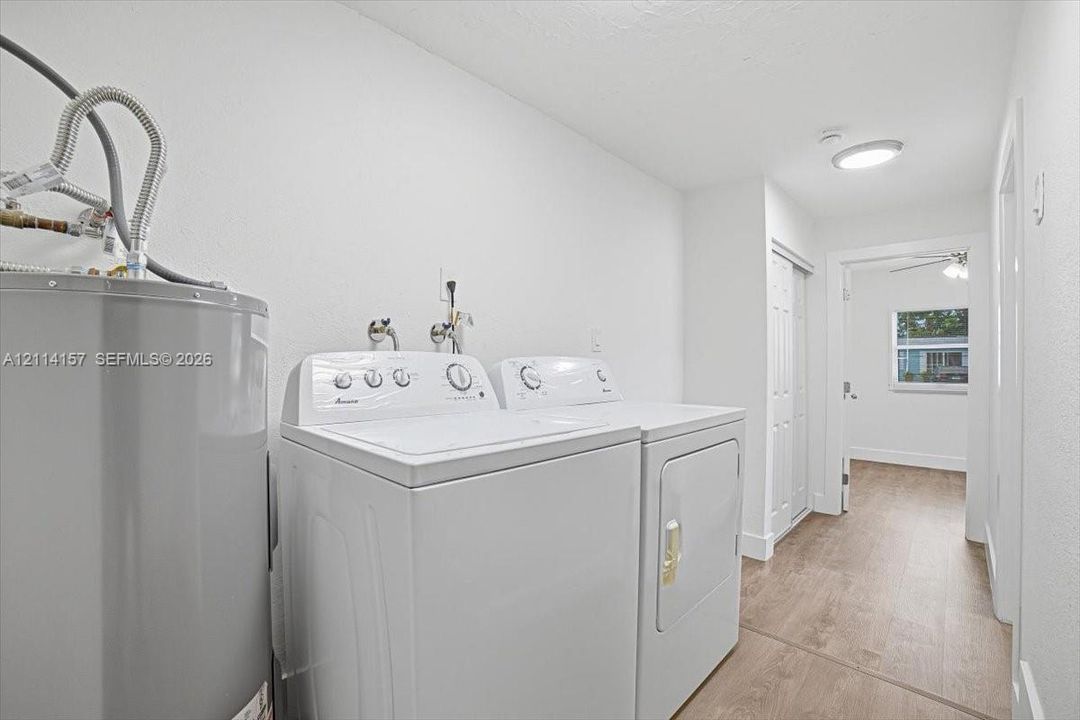 Laundry space featuring wood-finish flooring, ceiling-mounted lighting, and double-door closet storage