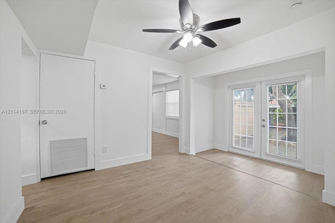 Interior space featuring wood-finish flooring, white walls, and a ceiling fan with integrated lighting