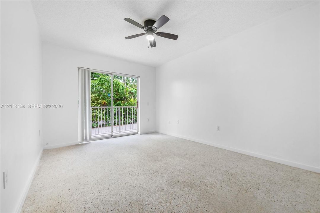 Room featuring neutral carpeting, a ceiling fan with integrated lighting, and sliding glass doors with a metal railing