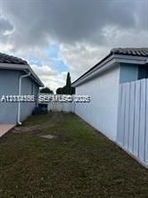 Exterior side yard featuring stucco walls, a tiled roof, and a perimeter privacy fence