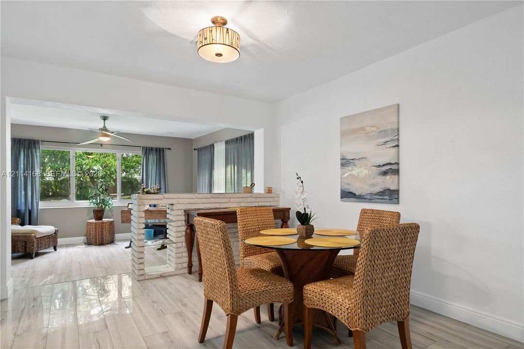 Italian Tile flooring throughout, low-profile brick partition wall, drum-style ceiling light fixture, ceiling fan, and large windows