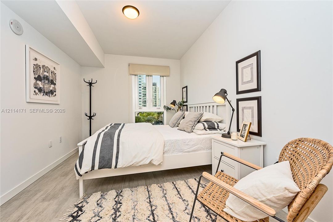 Wood-finish flooring, neutral wall tones, and floor-to-ceiling style window with a window shade