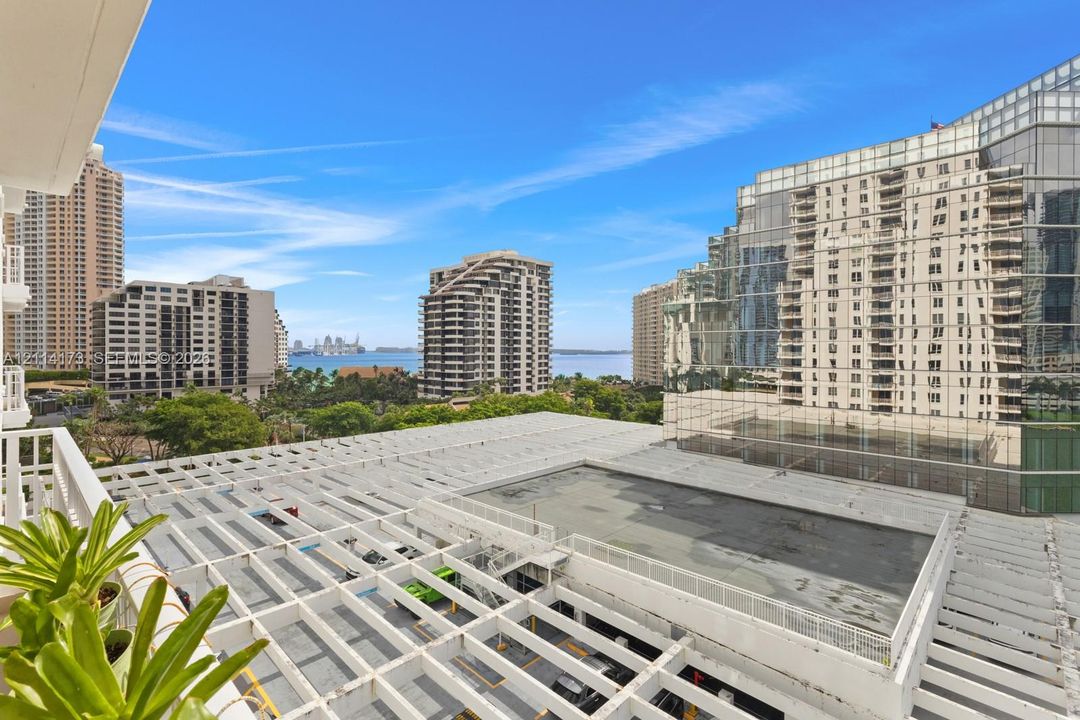 Private balcony featuring a structural white trellis overhead and a perspective of the surrounding urban skyline, waterfront, and marina