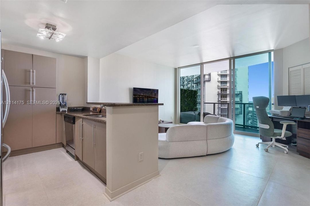 Kitchen featuring flat-panel cabinetry, stone countertops, and stainless steel appliances, with floor-to-ceiling windows and tile flooring