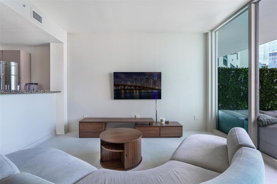 Open-concept interior featuring wall-to-wall carpeting, expansive floor-to-ceiling glass paneling, and a stone-topped breakfast bar