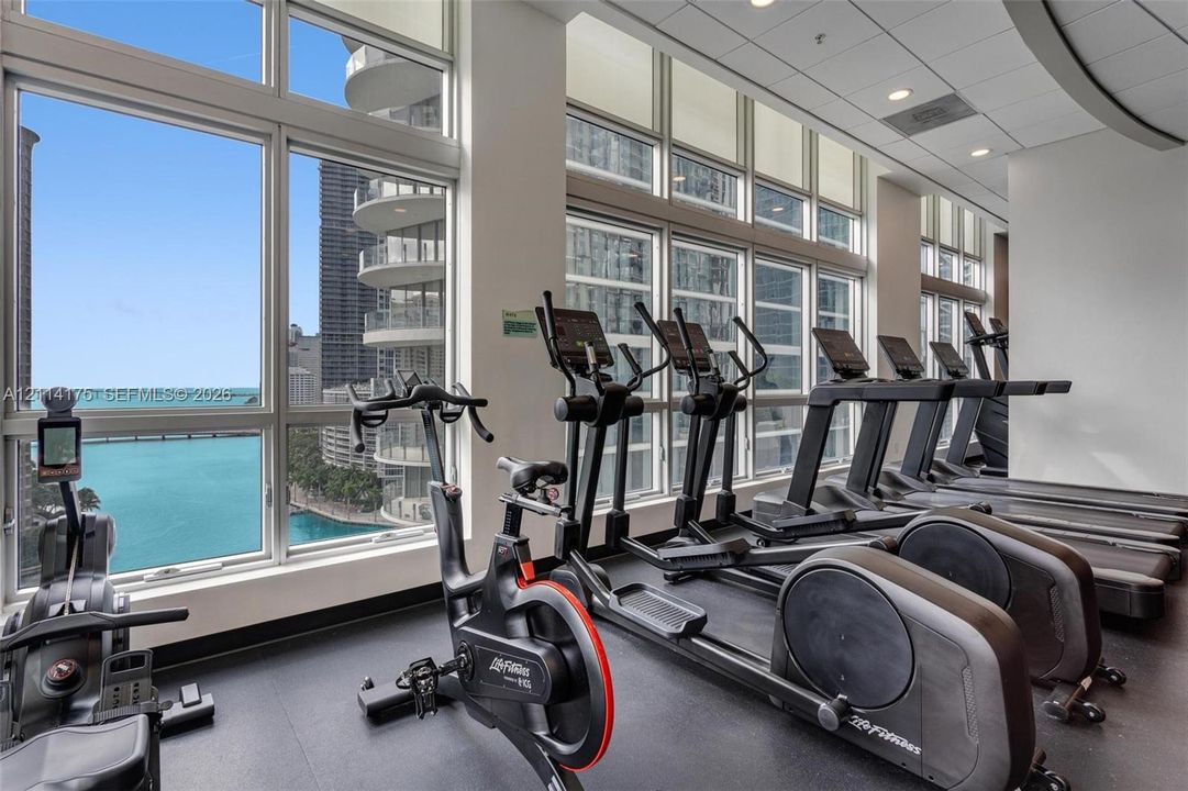 Fitness center featuring floor-to-ceiling windows, natural light, and rubber flooring