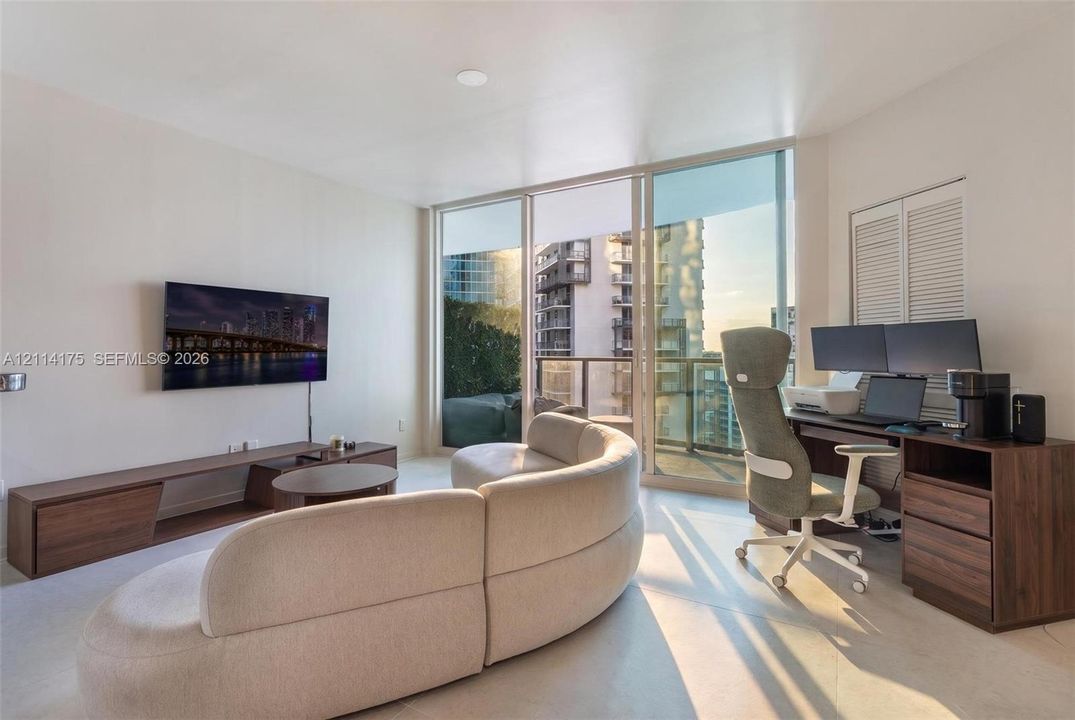 Floor-to-ceiling glass paneling, balcony access, neutral wall finishes, and louvered closet doors