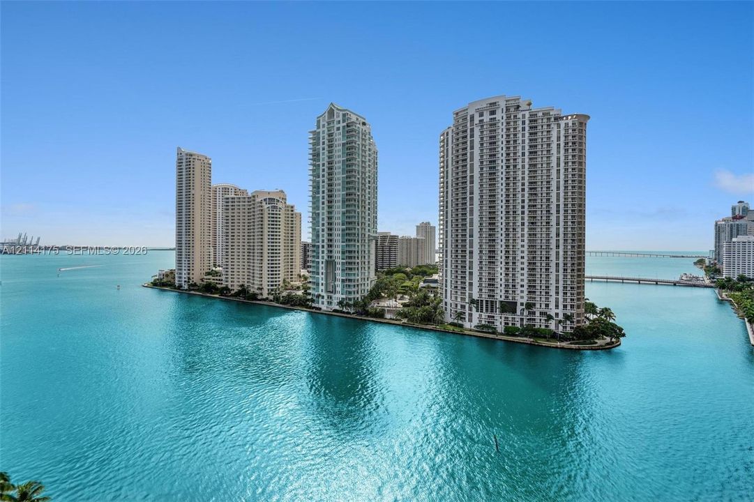 High-rise towers situated on a peninsula surrounded by water, featuring balcony levels and exterior glass detailing