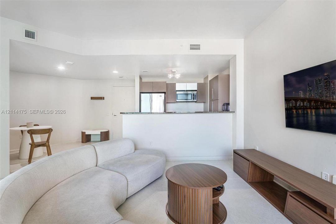 Open-concept interior featuring a breakfast bar with stone-surfaced countertop, neutral wall finishes, and recessed ceiling lighting