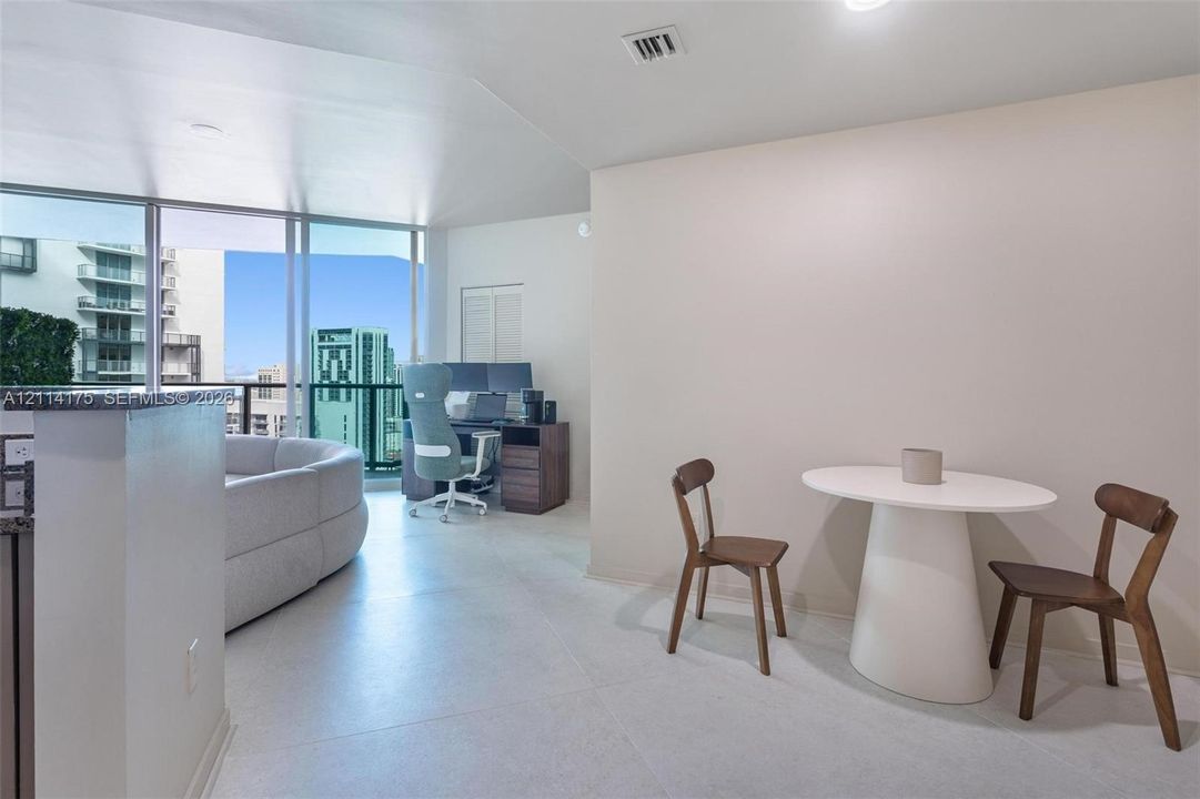Floor-to-ceiling windows with expansive urban skyline perspective, neutral large-format tile flooring, and solid-surface countertop