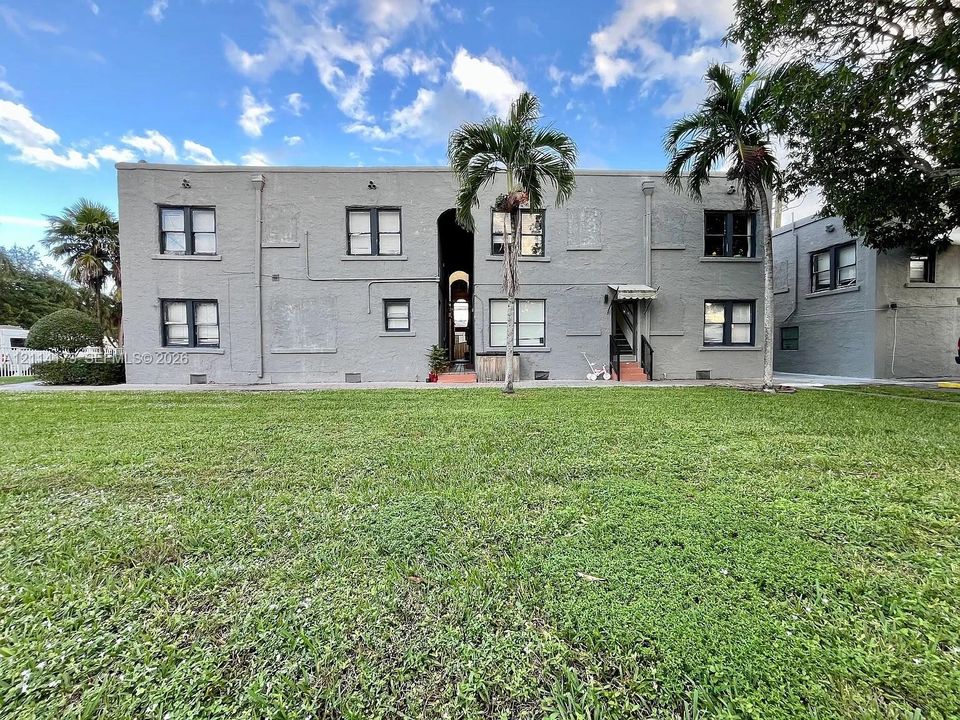 Multi-story masonry exterior with central arched entryway and expansive lawn