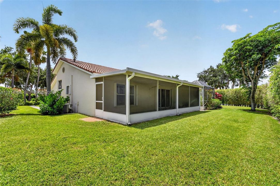 Exterior featuring a screen-enclosed patio, tile roof, stucco siding, and expansive manicured lawn