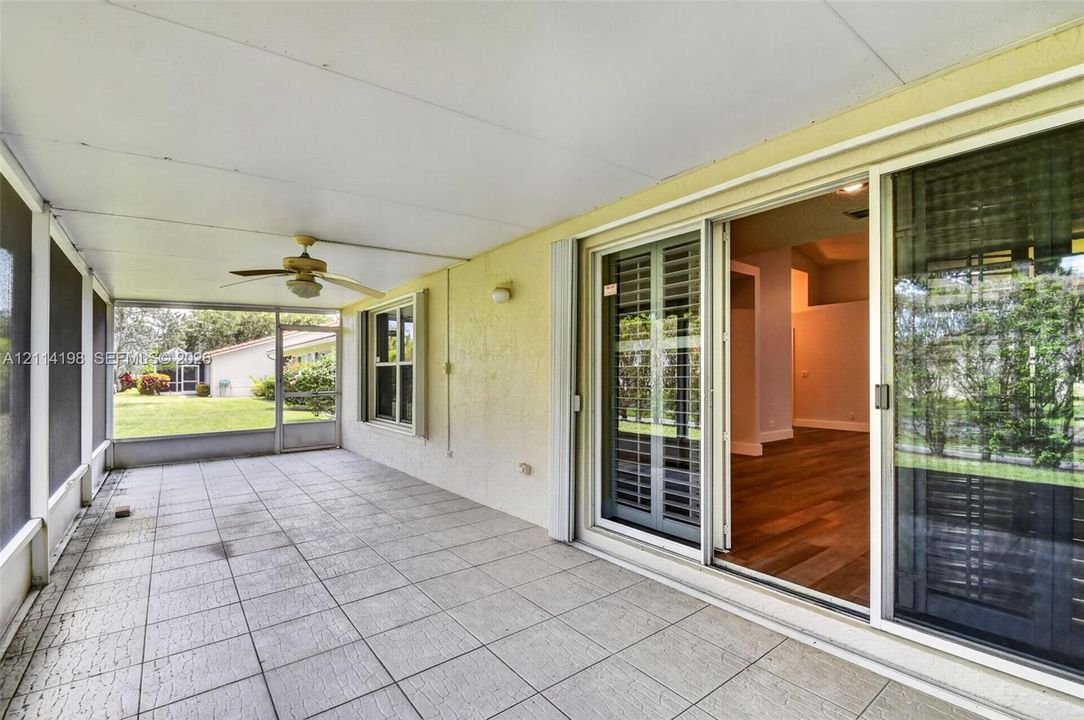 Screened-in patio featuring tile flooring, a ceiling fan, and sliding glass door access
