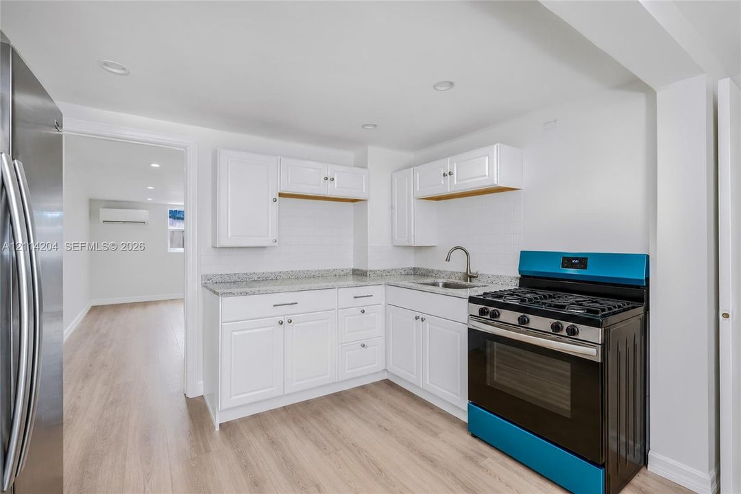Kitchen featuring white cabinetry, stone-finish countertops, stainless steel gas range, recessed lighting, and wood-finish flooring