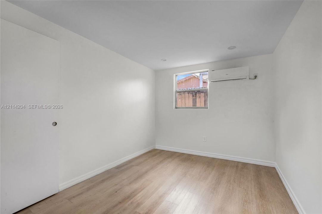 Interior room featuring wood-finish flooring, recessed ceiling lighting, a single-hung window, and a wall-mounted ductless climate control unit