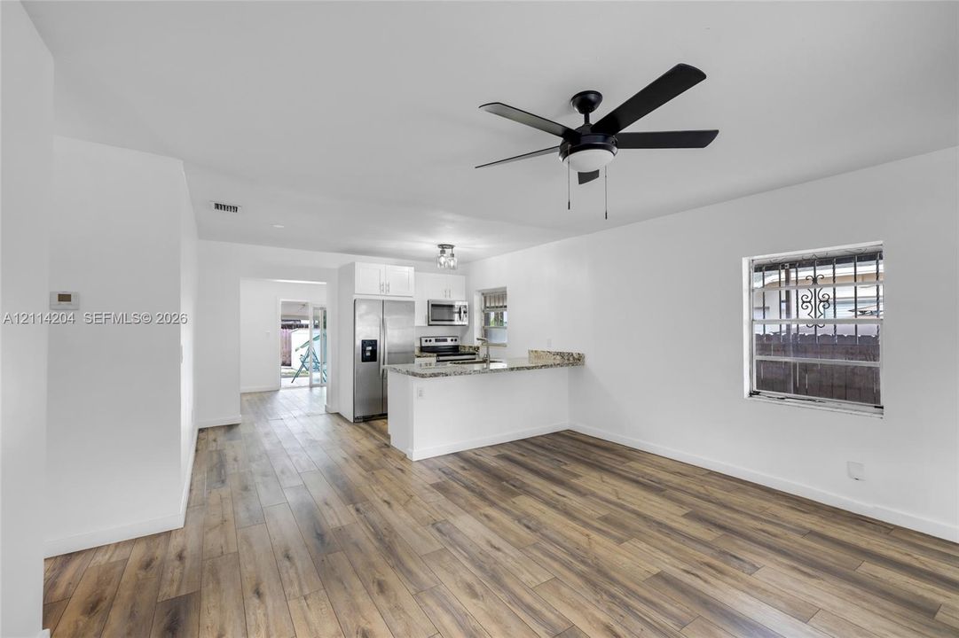 Kitchen featuring white cabinetry, stone-finish countertops, stainless steel appliances, wood-finish flooring, and a ceiling fan