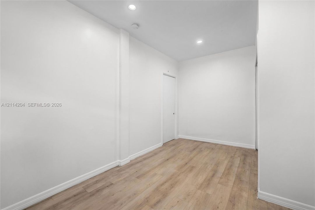 Interior space featuring wood-finish flooring, smooth white walls, and recessed ceiling lighting