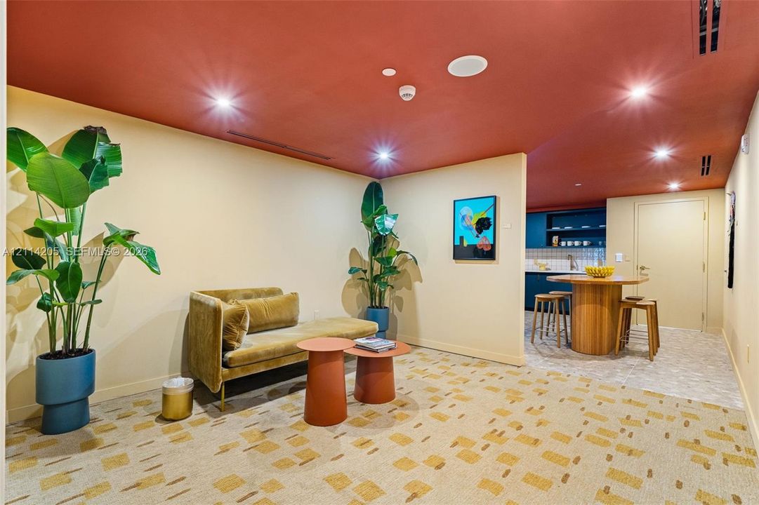 Interior space featuring a recessed ceiling with integrated lighting, patterned carpeting, and a kitchen area with built-in dark cabinetry and shelving - amenity