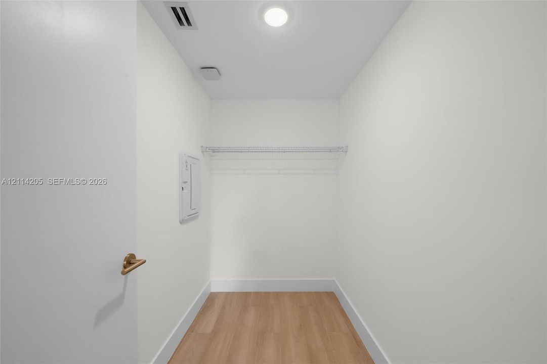 Enclosed storage space featuring wood-finish flooring, a white-coated wire shelf, and recessed ceiling lighting