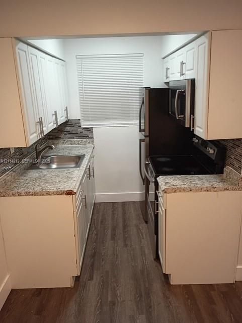 Kitchen featuring white cabinetry, stone-finish countertops, decorative tile backsplash, stainless steel appliances, and wood-finish flooring