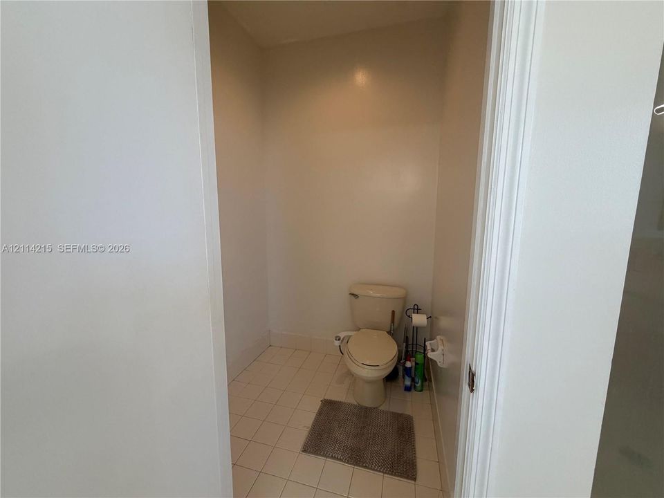 Enclosed water closet featuring light-toned tile flooring and neutral wall finishes