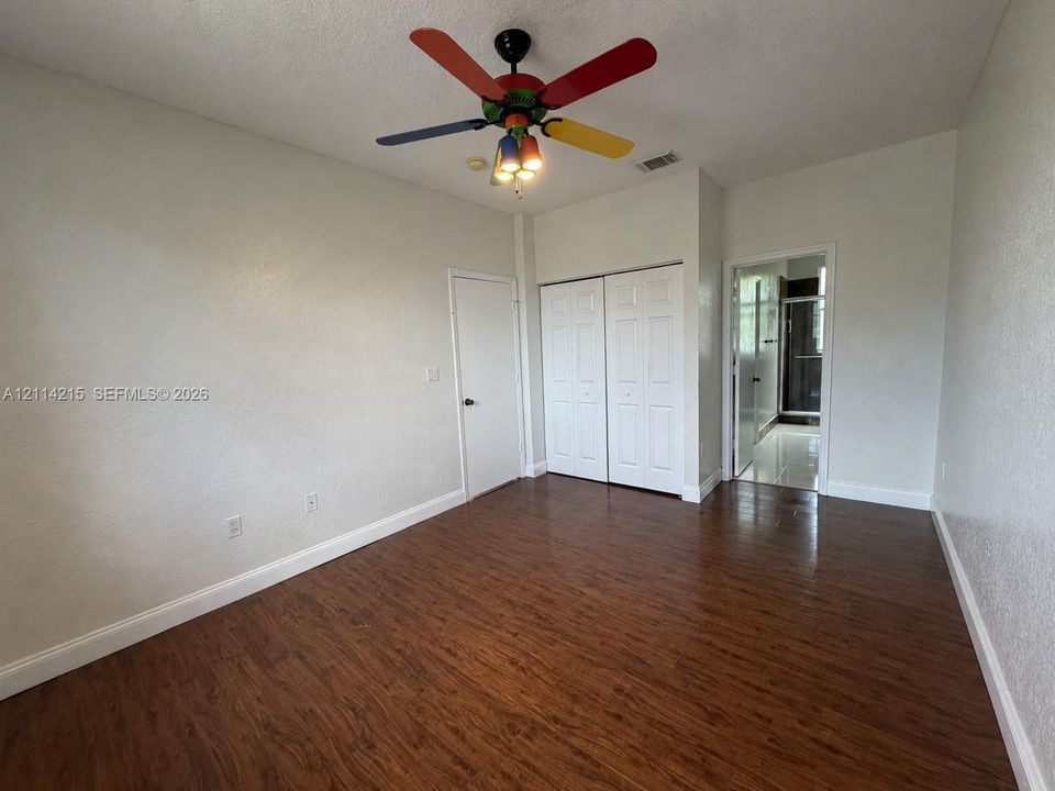 Room featuring wood-finish flooring, dual-door closet, and ceiling fan with integrated lighting