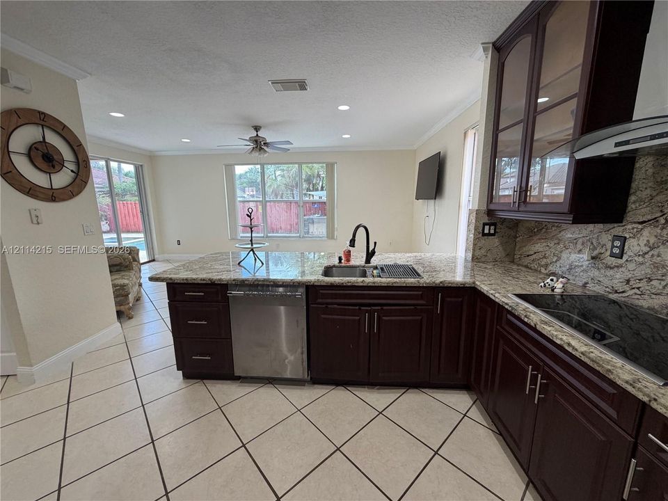 Kitchen featuring dark wood cabinetry, stone-surface countertops, stainless steel appliances, recessed ceiling lighting, and tile flooring