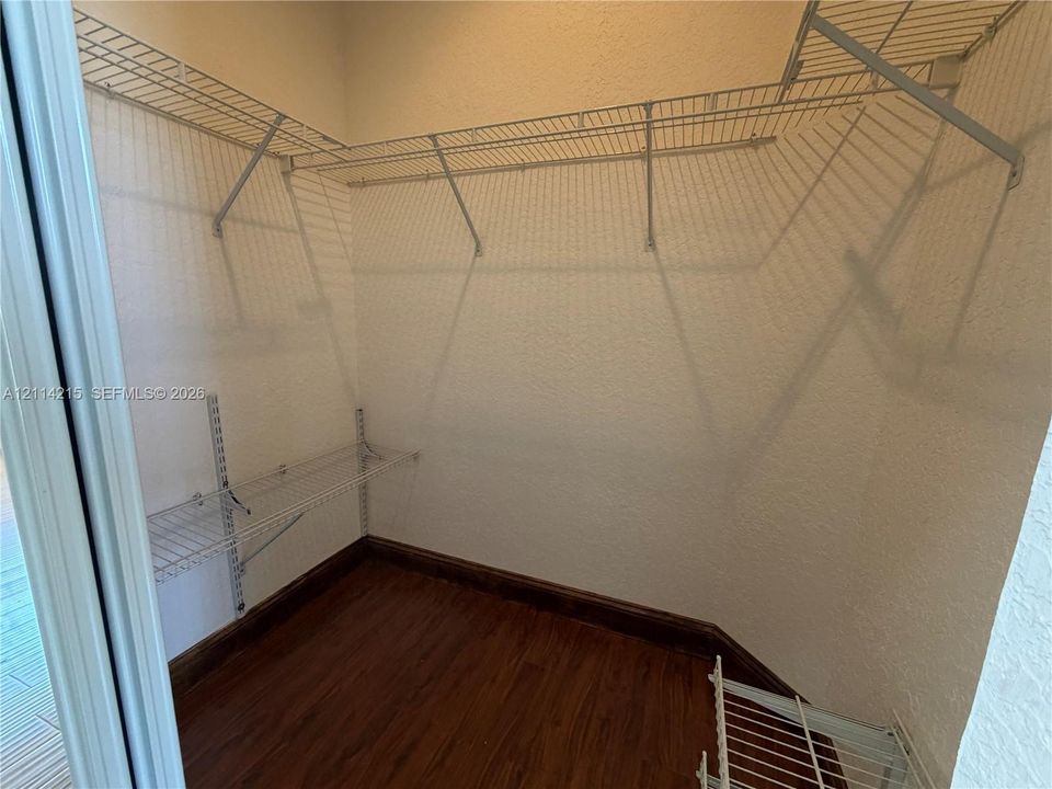 Walk-in closet featuring wood-finish flooring and tiered wire shelving