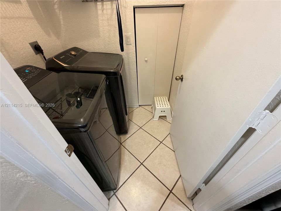 Laundry room featuring diagonal-set floor tile, textured wall finishes, and a bifold closet door