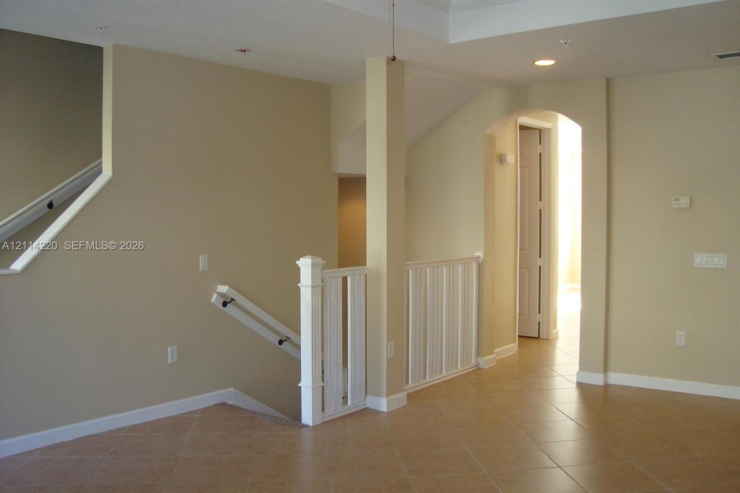 Interior space featuring ceramic tile flooring, tray ceilings, recessed lighting, and a white balustrade staircase